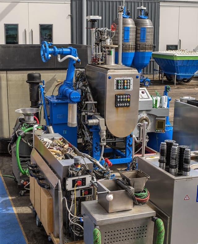 A stainless-steel food processing line with hoppers and control panels